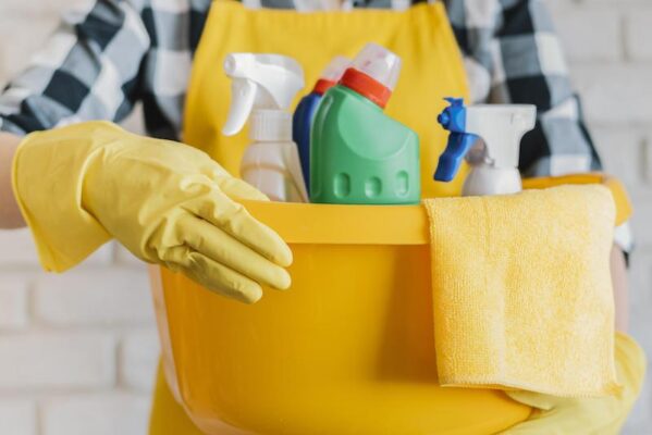 adult holding basket with cleaning products